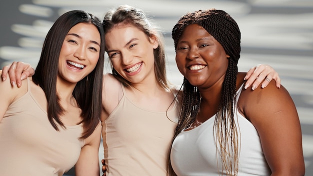 Modèles interraciaux maigres et courbés filmant une annonce de positivité corporelle, exprimant l'acceptation de soi et la confiance corporelle en studio. Femmes confiantes montrant la féminité pour la campagne de soins de la peau, concept d'amour de soi.