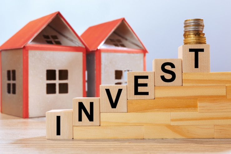 Photo modèles de maison et inscription sur des cubes en bois - investir. concept d'investissement immobilier.
