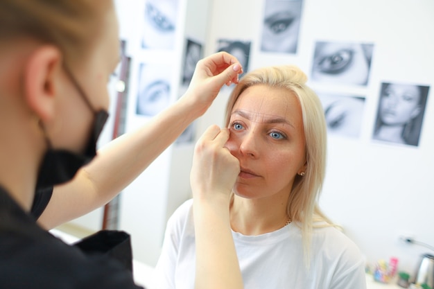 Le modeleur de sourcil de fille fait le balisage au client avec le fil