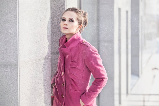 Modelez une belle femme dans un manteau à la mode à la surface du paysage urbain en hiver