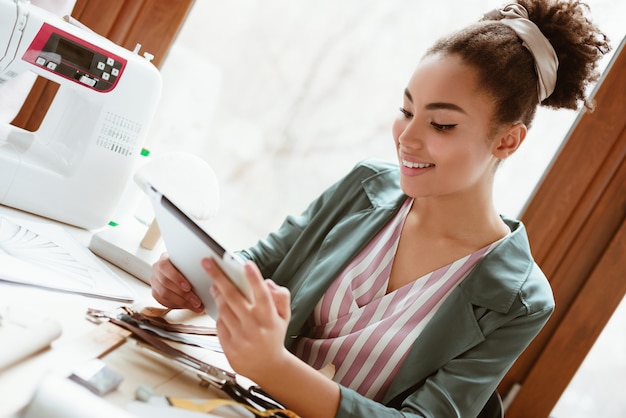 Modélisation D'un Nouveau Design Sur Tablette. Gros Plan Sur Un Tailleur De Jeune Femme Avec Une Tablette Numérique Modélise De Nouveaux Vêtements Dans Un Studio De Design