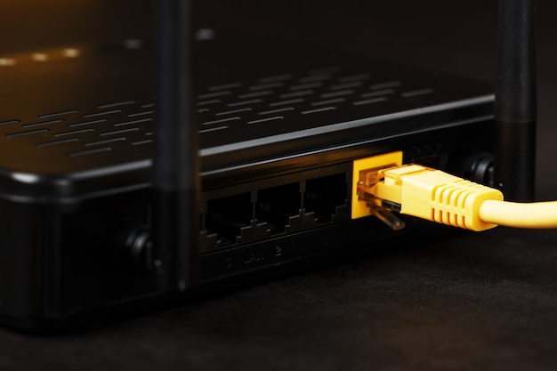 Modem routeur sans fil avec câble jaune et port LAN pour connexion sur fond noir.