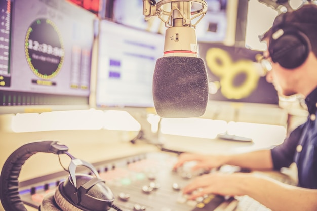 Le modérateur radio est assis dans un studio de diffusion moderne et parle dans le microphone