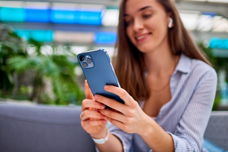 Photo modern happy attractive casual smiling smart millénaire femme portant des écouteurs sans fil à l'aide de téléphone pour la navigation en ligne et le chat