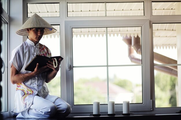 Moine asiatique en kimono lisant un vieux livre