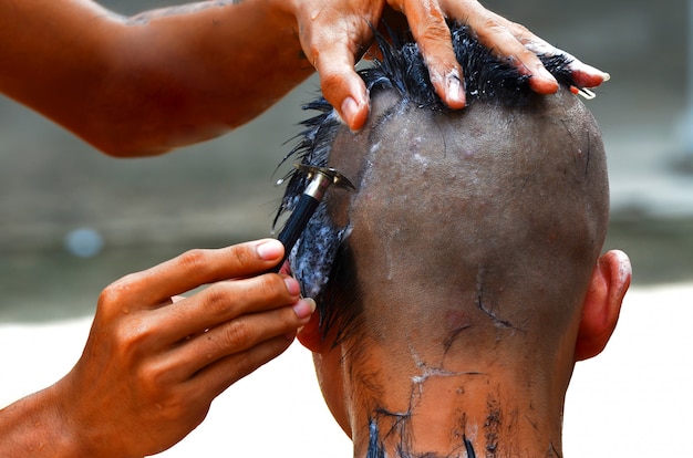 Moine dans le bouddhisme utilise une tondeuse pour se raser