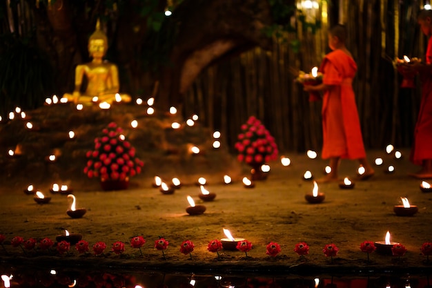 Des moines assis méditent avec de nombreuses bougies dans un temple thaïlandais la nuit