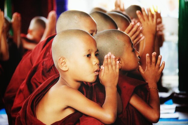 Photo des moines bouddhistes novices avec les mains jointes prient dans le temple