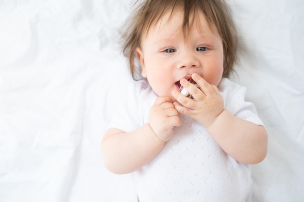 Mois de bébé garçon mignon avec mamelon allongé sur une literie blanche à la maison vue de dessus