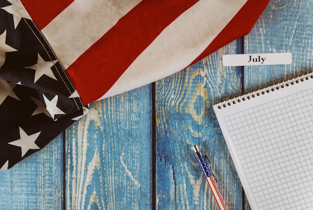 Mois de juillet de l'année civile États-Unis d'Amérique drapeau du symbole de la liberté et de la démocratie avec bloc-notes vierge et stylo sur la table en bois de bureau