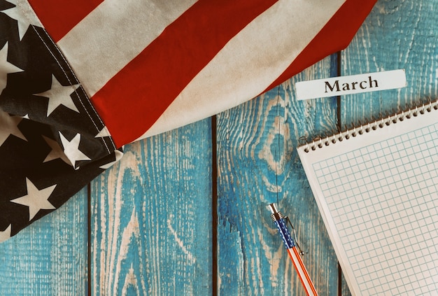 Mois de mars de l'année civile États-Unis d'Amérique drapeau du symbole de la liberté et de la démocratie avec bloc-notes vide et stylo sur table en bois de bureau