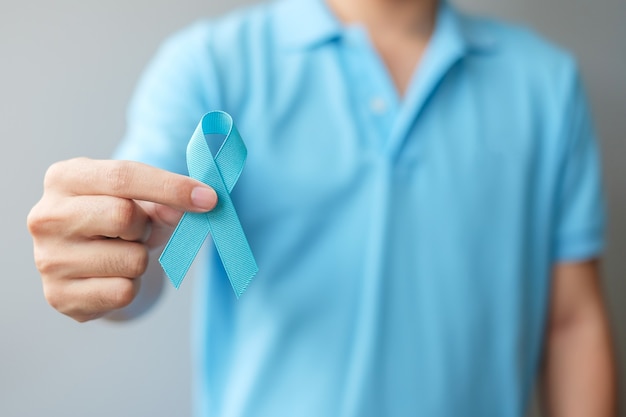 Mois de sensibilisation au cancer de la prostate de novembre, homme en chemise bleue avec la main tenant le ruban bleu pour soutenir les personnes vivant et malades. Soins de santé, hommes internationaux, père et concept de la journée mondiale du cancer