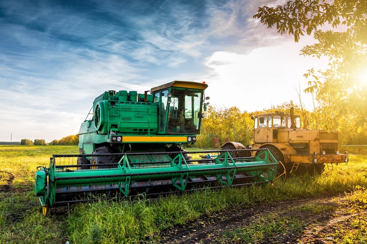 Photo la moissonneuse-batteuse verte moderne et le tracteur robuste jaune sur le terrain agricole dans les rayons du soleil d'automne