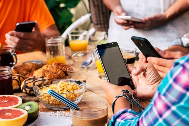 Une moitié d'amis utilisant des téléphones portables à la table dans un restaurant.