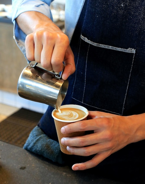 La moitié d'un barista versant du café dans un café