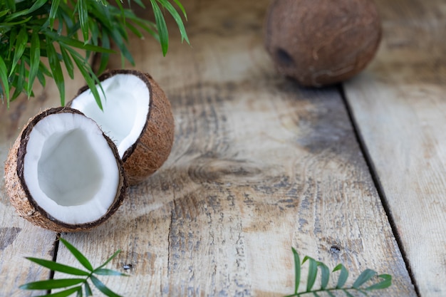 La moitié de la branche de noix de coco et de palmier se trouvent sur une table en bois.