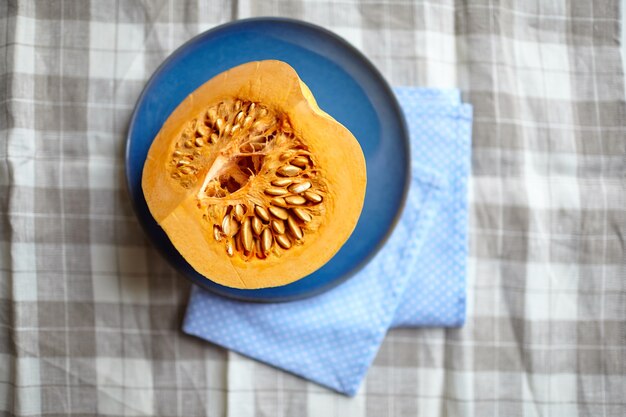 La moitié de la citrouille sur une plaque bleue sur une table, vue du dessus, ingrédient végétal