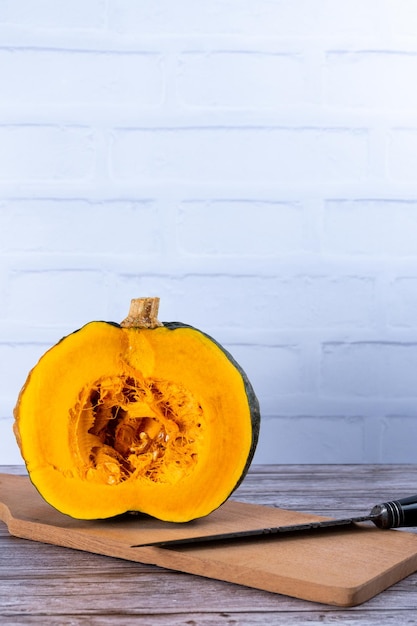 La moitié d'une courge cabutia sur une planche de bois et avec un couteau