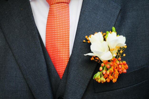 Photo la moitié du marié avec des fleurs dans la poche