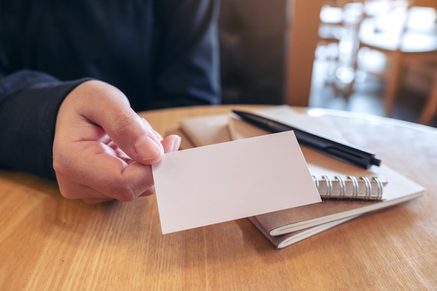 Photo la moitié d'une femme donnant une carte de visite blanche sur la table