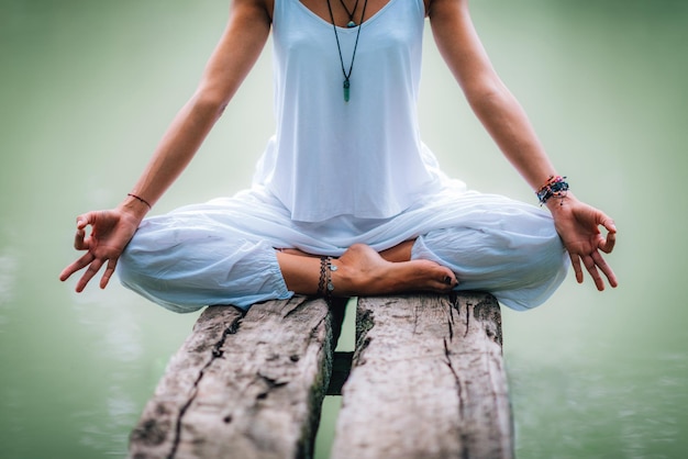 Photo la moitié d'une femme faisant du yoga assise sur une jetée au lac