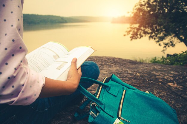 Photo la moitié d'une femme lisant un livre sur la mer au coucher du soleil