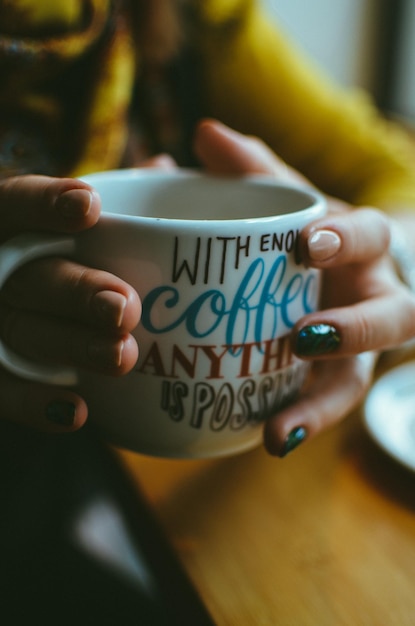 La moitié d'une femme tenant du café alors qu'elle est assise à la table dans un café