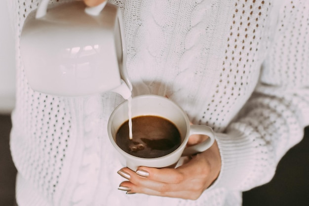 La moitié d'une femme versant du lait dans le café