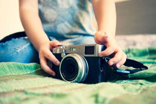 Photo la moitié d'une fille tenant une caméra sur le lit