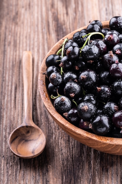 Moitié d&#39;un grand bol en bois avec cassis et cuillère