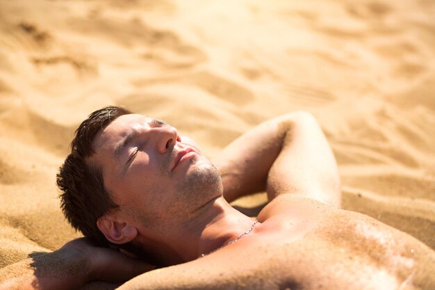 Photo la moitié d'un homme allongé sur le sable