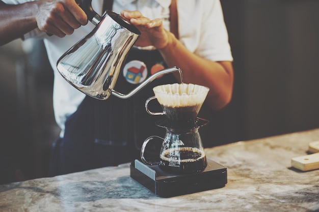 La moitié d'un homme préparant du café sur la table