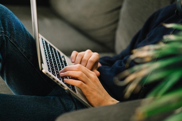 La moitié de l'homme utilisant un ordinateur portable alors qu'il est allongé sur le canapé à la maison