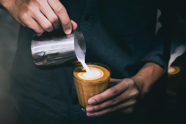 La moitié d'un homme versant du lait dans une tasse de café