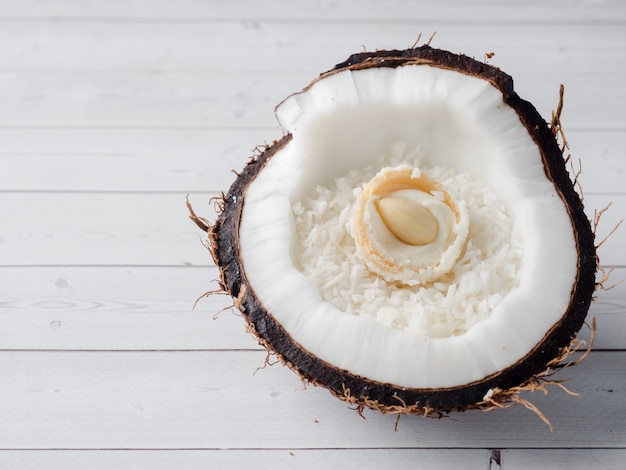 La moitié de la noix de coco bio fraîche avec des bonbons à la noix de coco et au chocolat à l&#39;intérieur sur fond en bois.