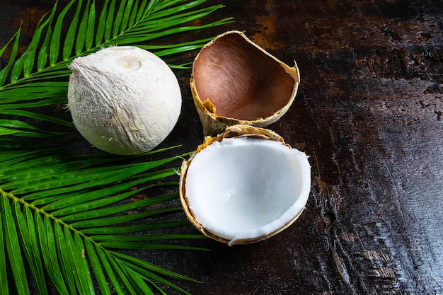 La moitié de la noix de coco avec des feuilles sur fond en bois