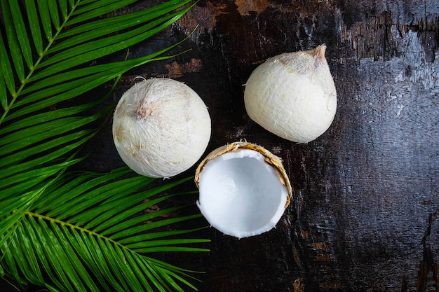 La moitié de la noix de coco avec des feuilles sur fond en bois