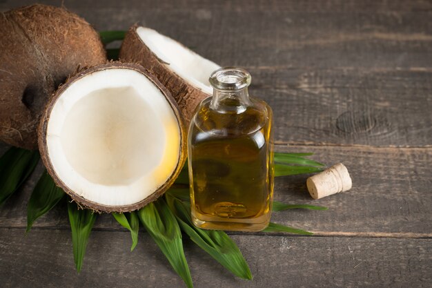 La moitié de la noix de coco mûre coupée avec des feuilles vertes sur un fond en bois