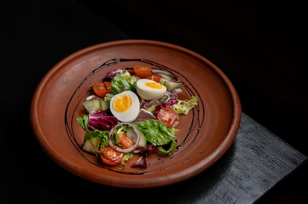 La moitié d'un œuf à la coque avec des légumes salade de tomates oignon L'assiette est sur le coin de la table