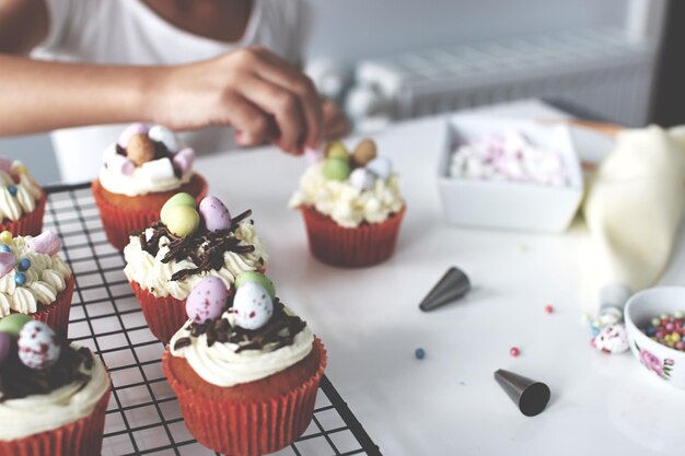 La moitié d'une personne garnissant des cupcakes sur la table à la maison