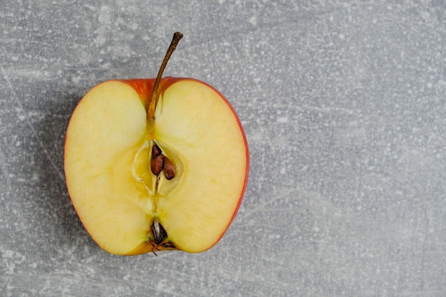 La moitié de la pomme rouge coupée se trouve sur un fond de béton