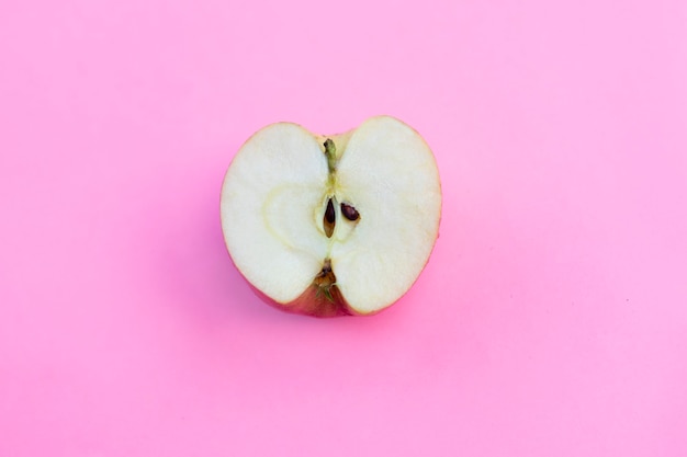 La moitié de la pomme se trouve sur un fond rose