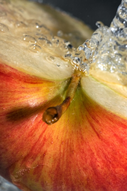 Photo la moitié d'une pomme sucrée mûre rouge sous un courant d'eau propre macrophotographie en gros plan