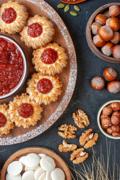 moitié supérieure vue biscuits avec confiture et bol de confiture sur planche de bois noix dans des bols sur tableau noir