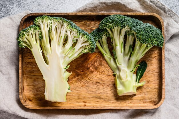 Moitiés de brocoli frais dans un bol en bois. Fond gris. Vue de dessus