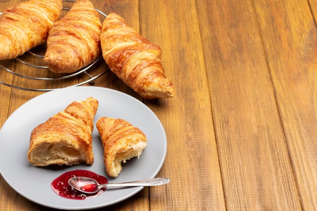 Moitiés de croissant et cuillère avec de la confiture sur une soucoupe. Espace de copie. Vue de dessus. Fond en bois