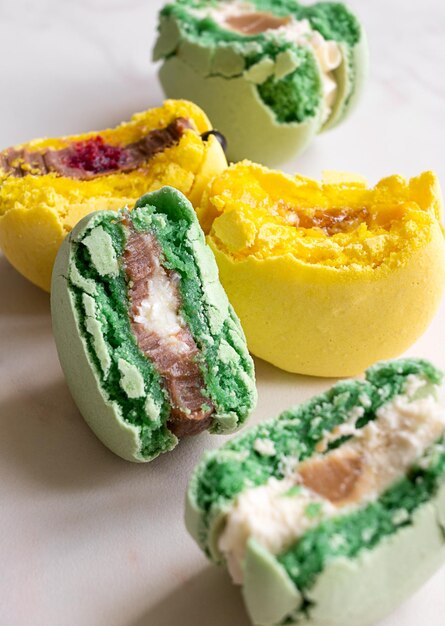 Photo moitiés de macarons français verts et jaunes avec différentes garnitures verticales
