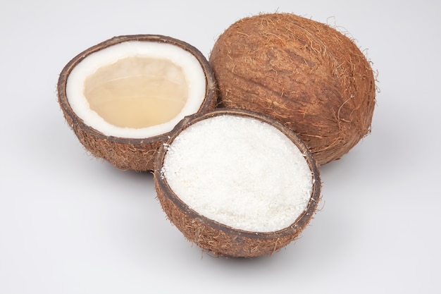 Moitiés de noix de coco avec noix de coco, lait et pulpe sur fond blanc