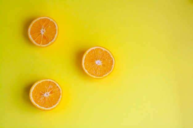 Moitiés d'orange mûre sur une table jaune, vue de dessus