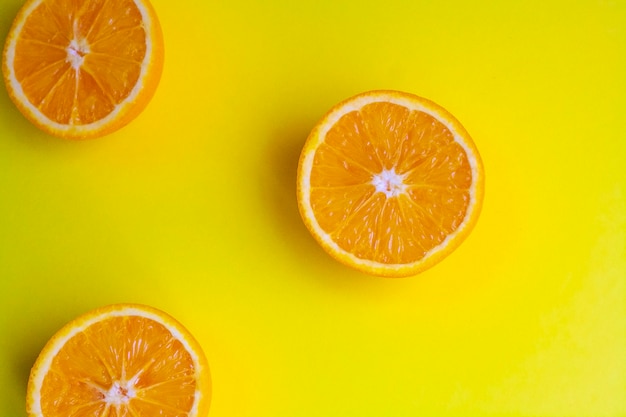 Moitiés oranges sur une table jaune, vue de dessus